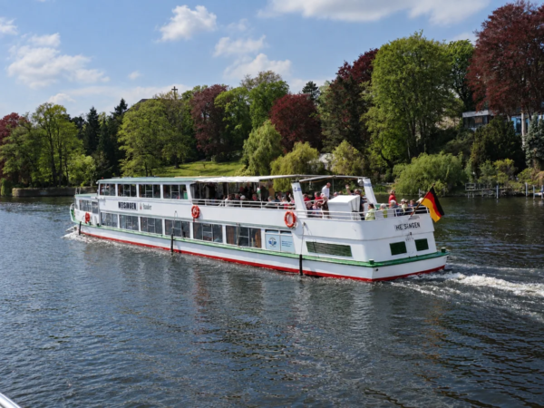 Weißes Ausflugsschiff auf dem Baldeneysee vor bewaldetem Ufer