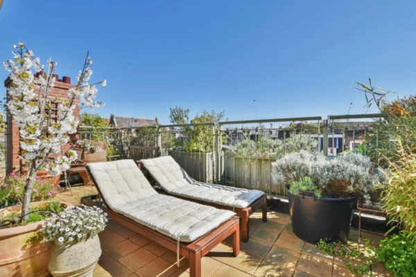 Dachterrasse mit Liegestühlen und Pflanzen über den Dächern der Stadt