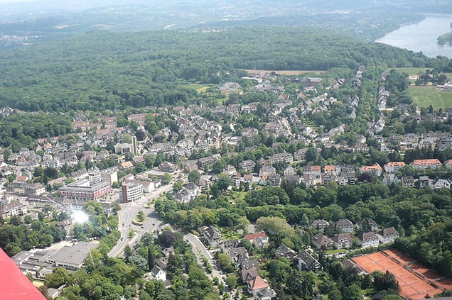 Luftaufnahme des Vorortgebiets Essen Stadtwald mit von Bäumen gesäumten Straßen und Wohngebäuden im Hintergrund.