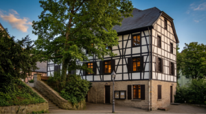 Historisches Fachwerkhaus in Essen-Werden mit steinernem Sockel, Außentreppe und altem Straßenlaternenmast.