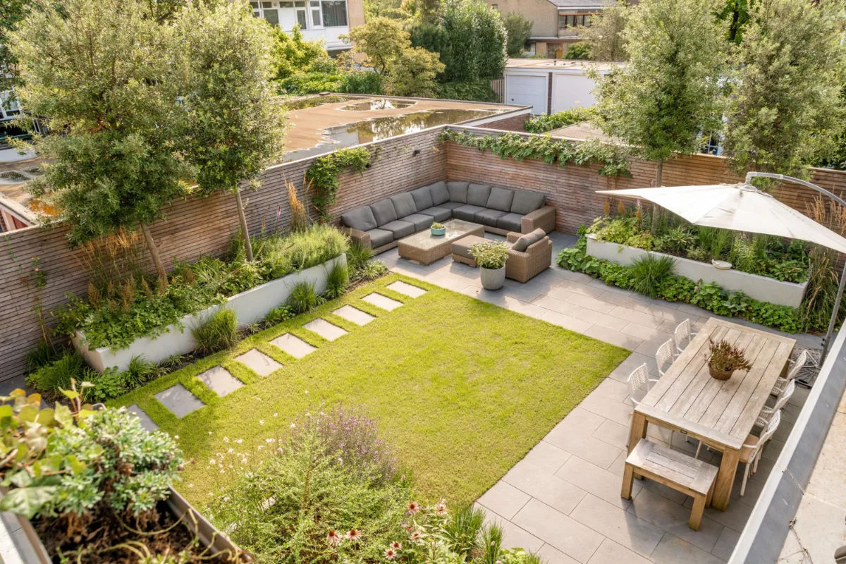 Luftaufnahme eines gepflegten Gartens mit Terrasse, Sitzecke und Rasenfläche