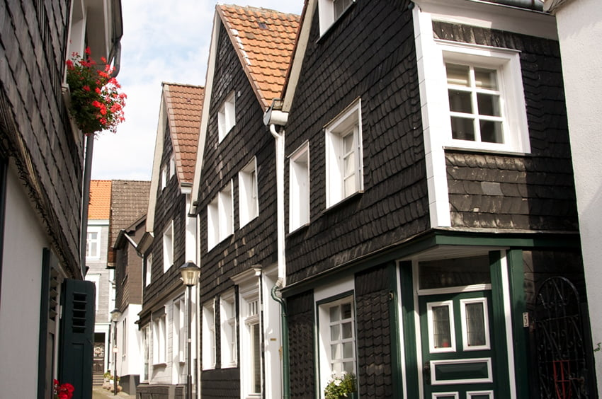 Schmale historische Gasse mit schieferverkleideten Häusern und weißen Fenstern.