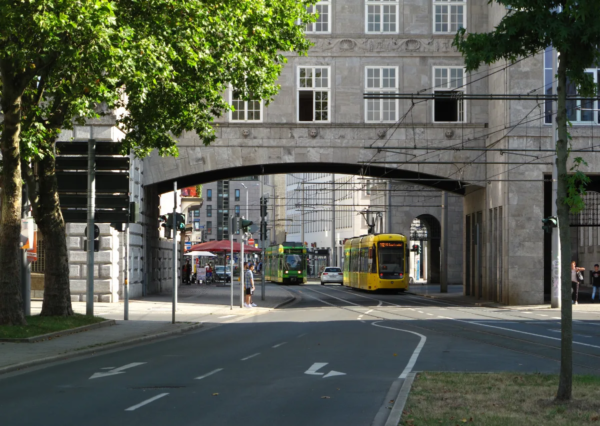Gelbe Straßenbahn fährt unter einem Torbogen in einem historischen Gebäude in Mülheim an der Ruhr