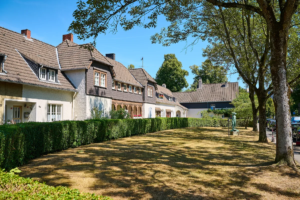 Wohnhäuser hinter Hecken an einer grünen Straße in Essen-Rüttenscheid
