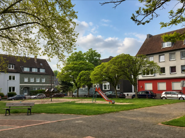 Ruhige Wohnstraße mit Spielplatz und Bäumen in Essen
