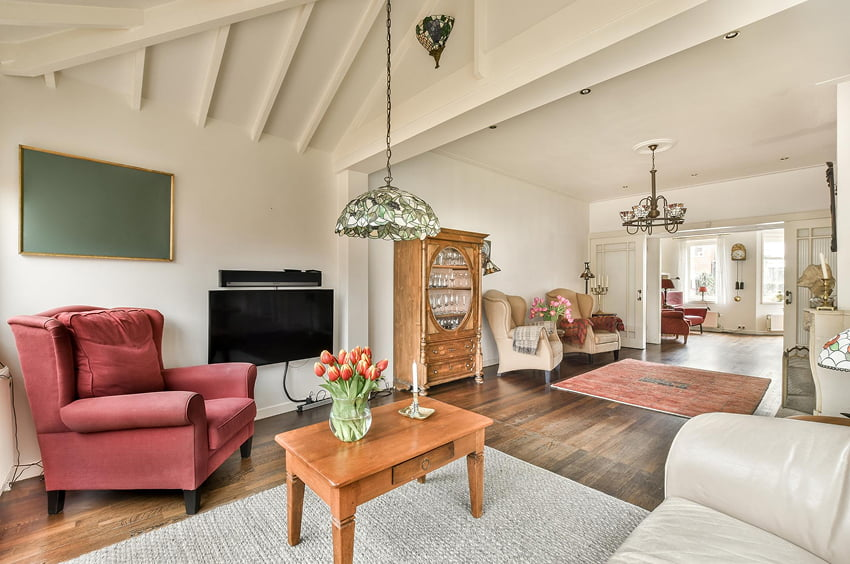 Helles Wohnzimmer mit Holzboden, Sitzmöbeln und klassischer Einrichtung.